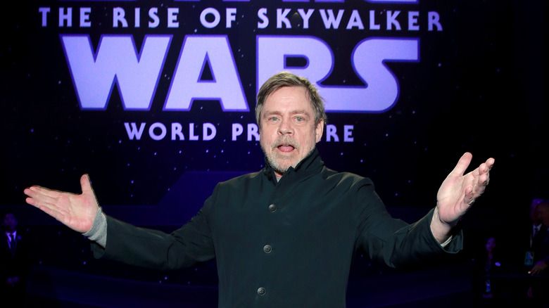 Mark Hamill segurando as mãos para cima em um evento