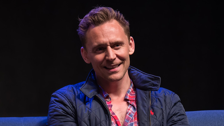   Tom Hiddleston somrient mentre estava assegut a l'escenari