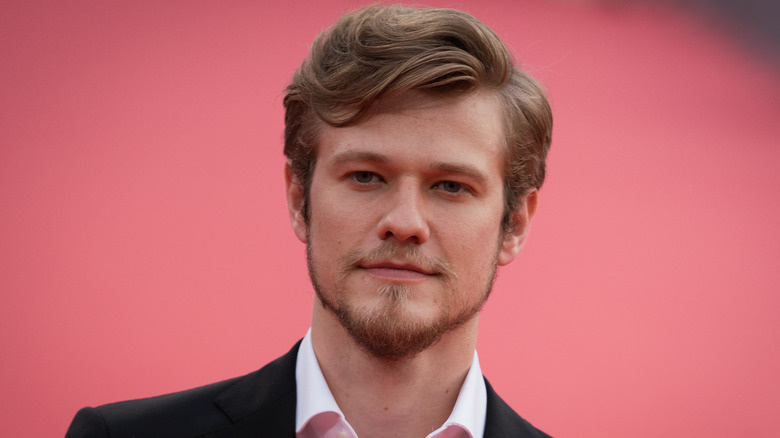   Lucas Till posant sobre una catifa vermella