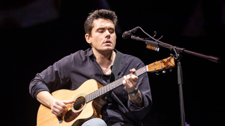   John Mayer a l'escenari tocant la guitarra davant d'un micròfon