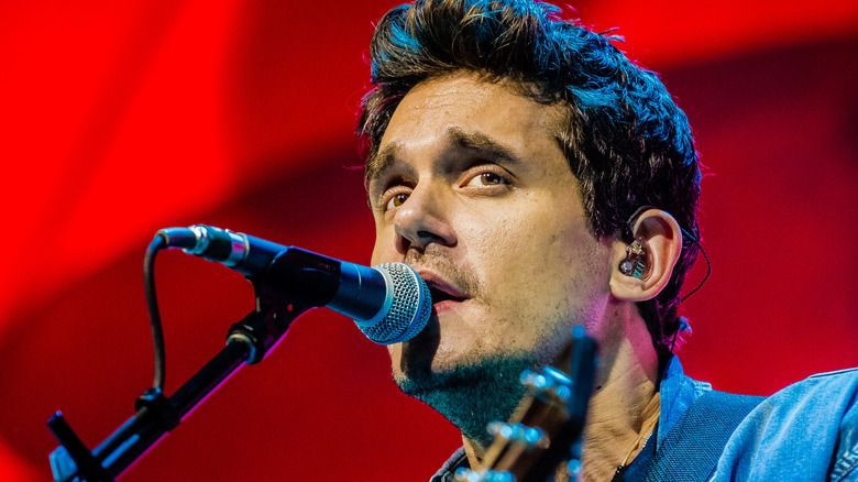 John Mayer synger i en mikrofon på scenen