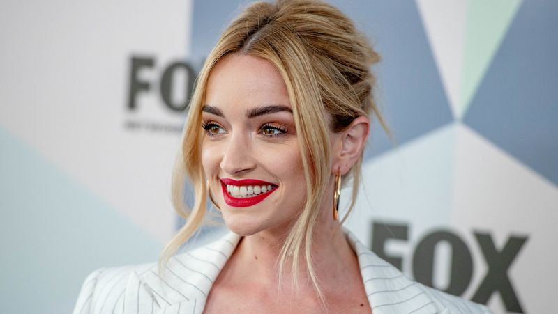 Brianne Howey se při pózování na akci usmívá